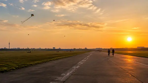 Startbahn auf dem Tempelhofer Feld im Abendlicht mit Drachen am Himmel